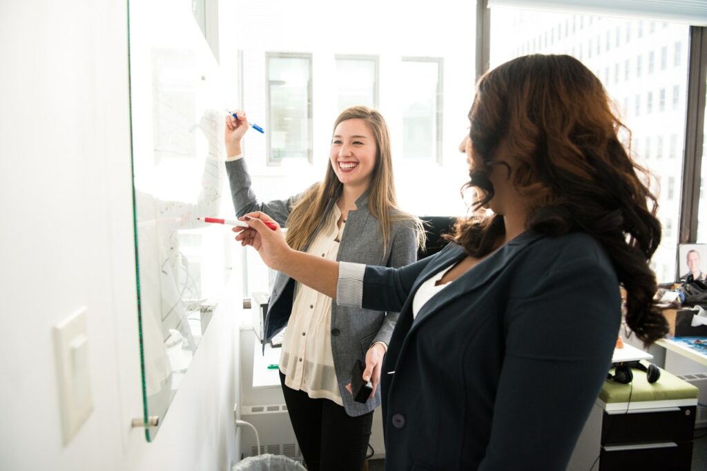 Two business woman sketching Onboarding process on white board