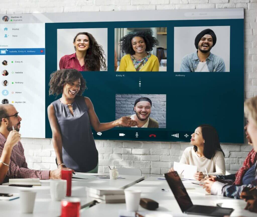 group of employees in conference room collaboratively working with virtual team on video call.
 