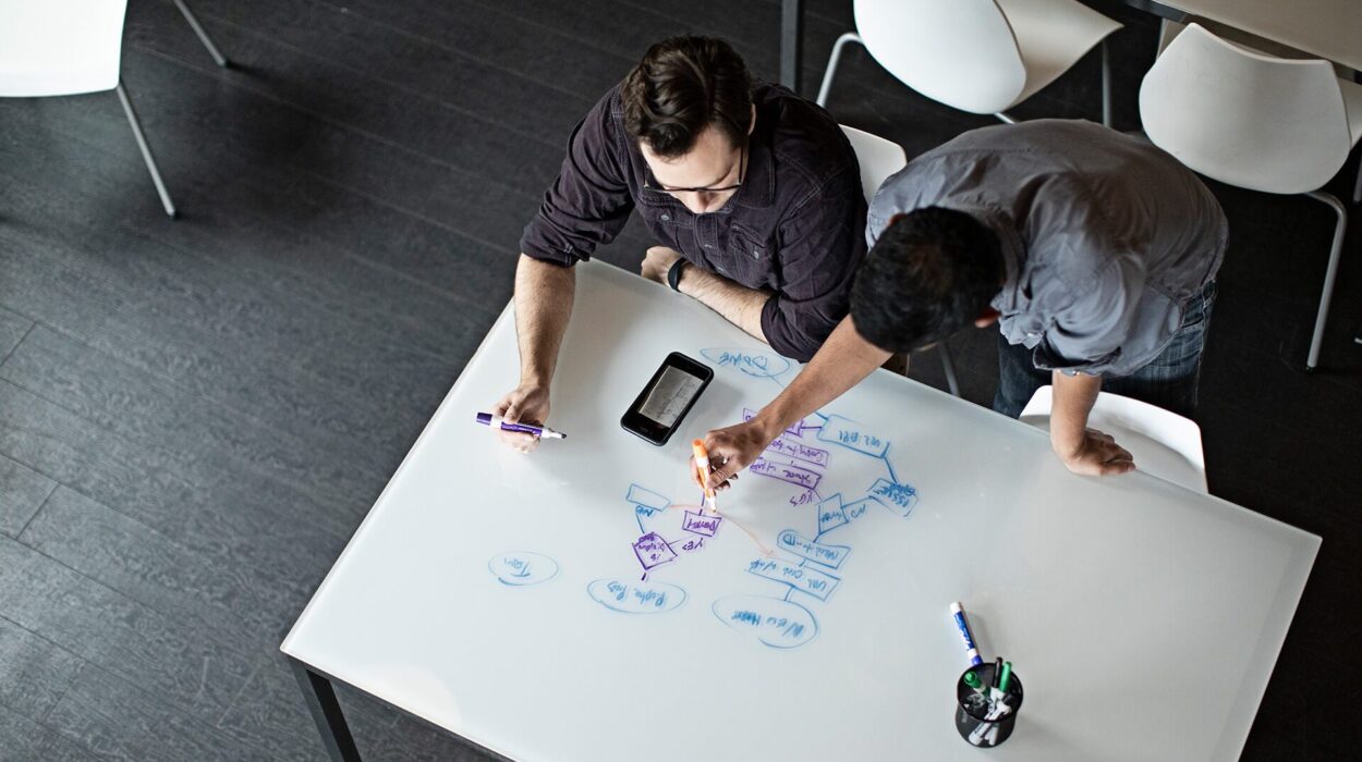 Top view of Data engineers drawing analytics modernization flowchart on white desk with blue and violet sketches.