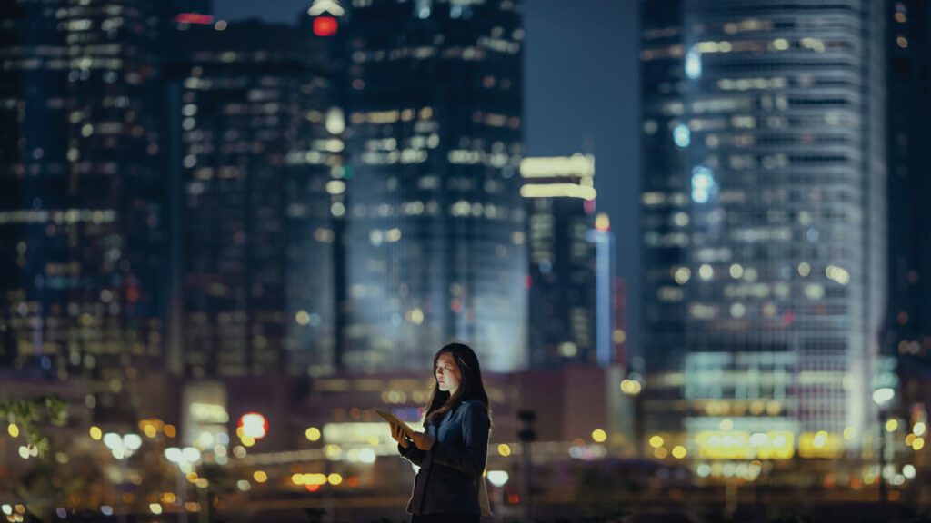 A women standing in front of tall buildings & working on edge computing