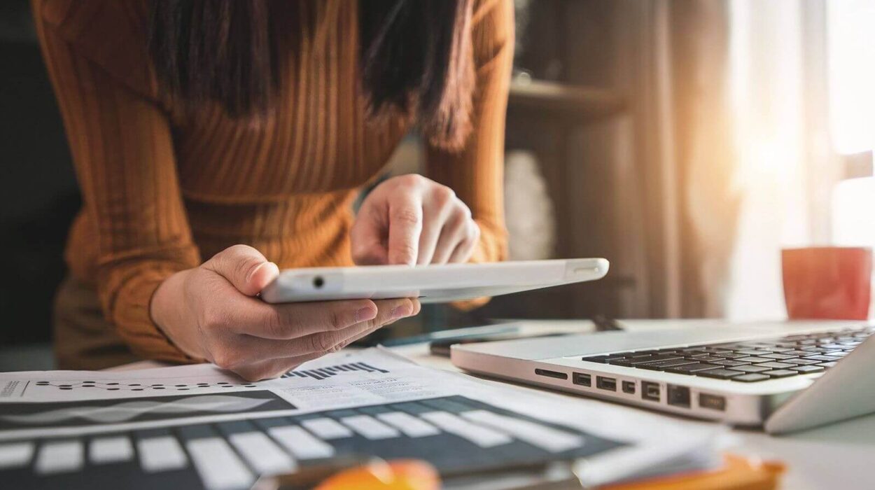 woman using ipad and her desk is occupied with digital marketing reports and laptop.
