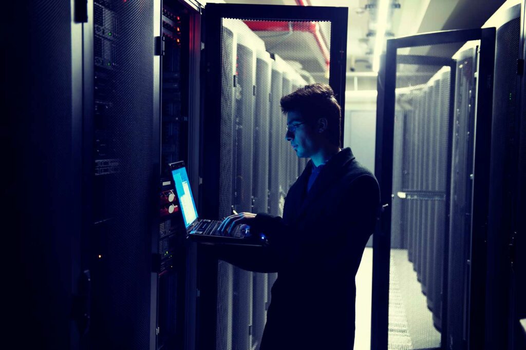 a man reviewing servers, working on laptop managing government cybersecurity